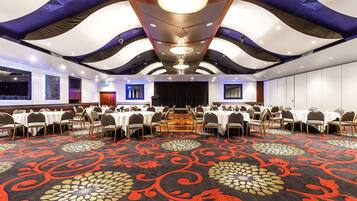 A conference room with round tables, chairs, and a patterned carpet.