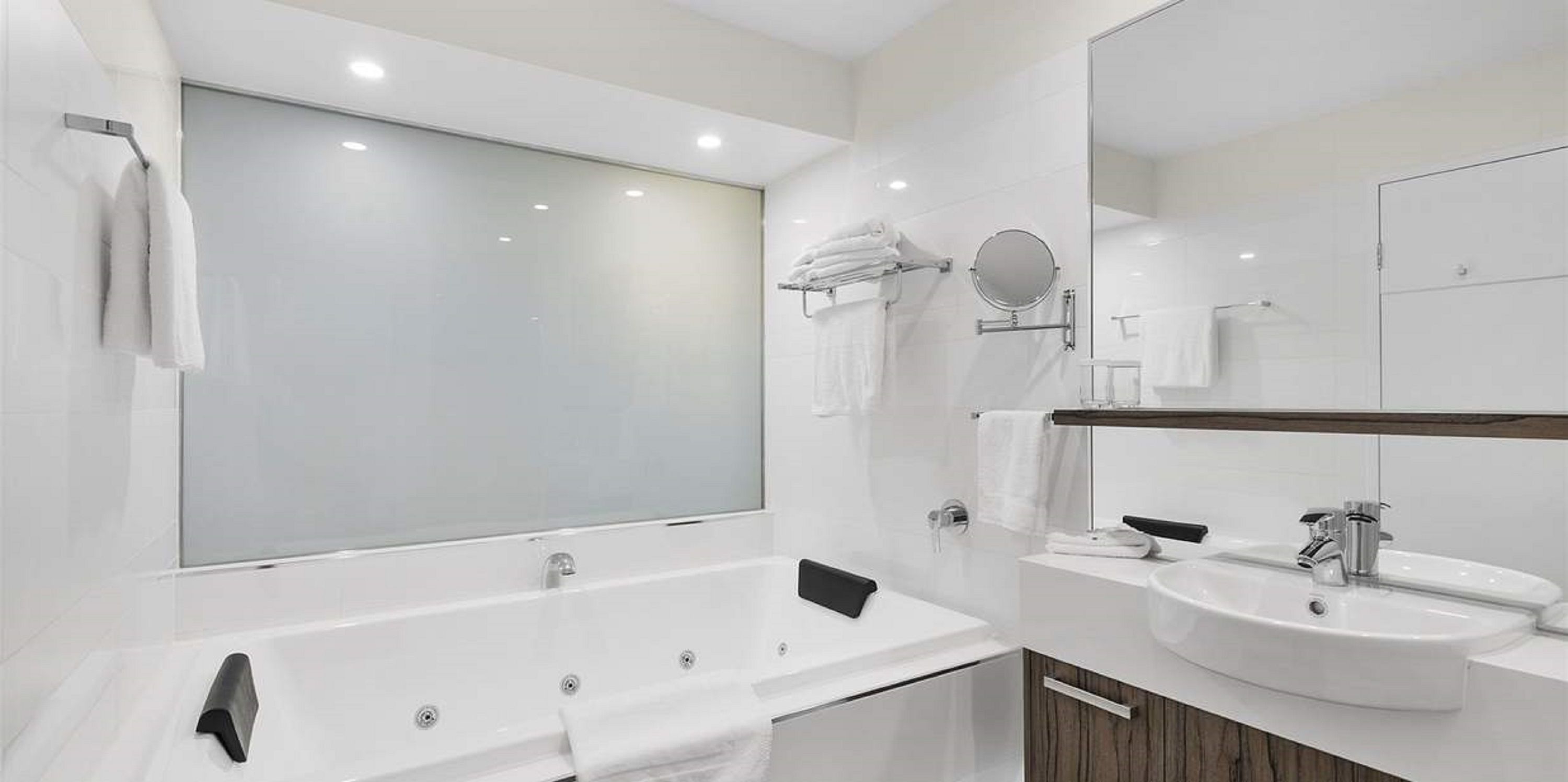 Un baño moderno con una bañera grande, un tocador con lavamanos y un espejo.