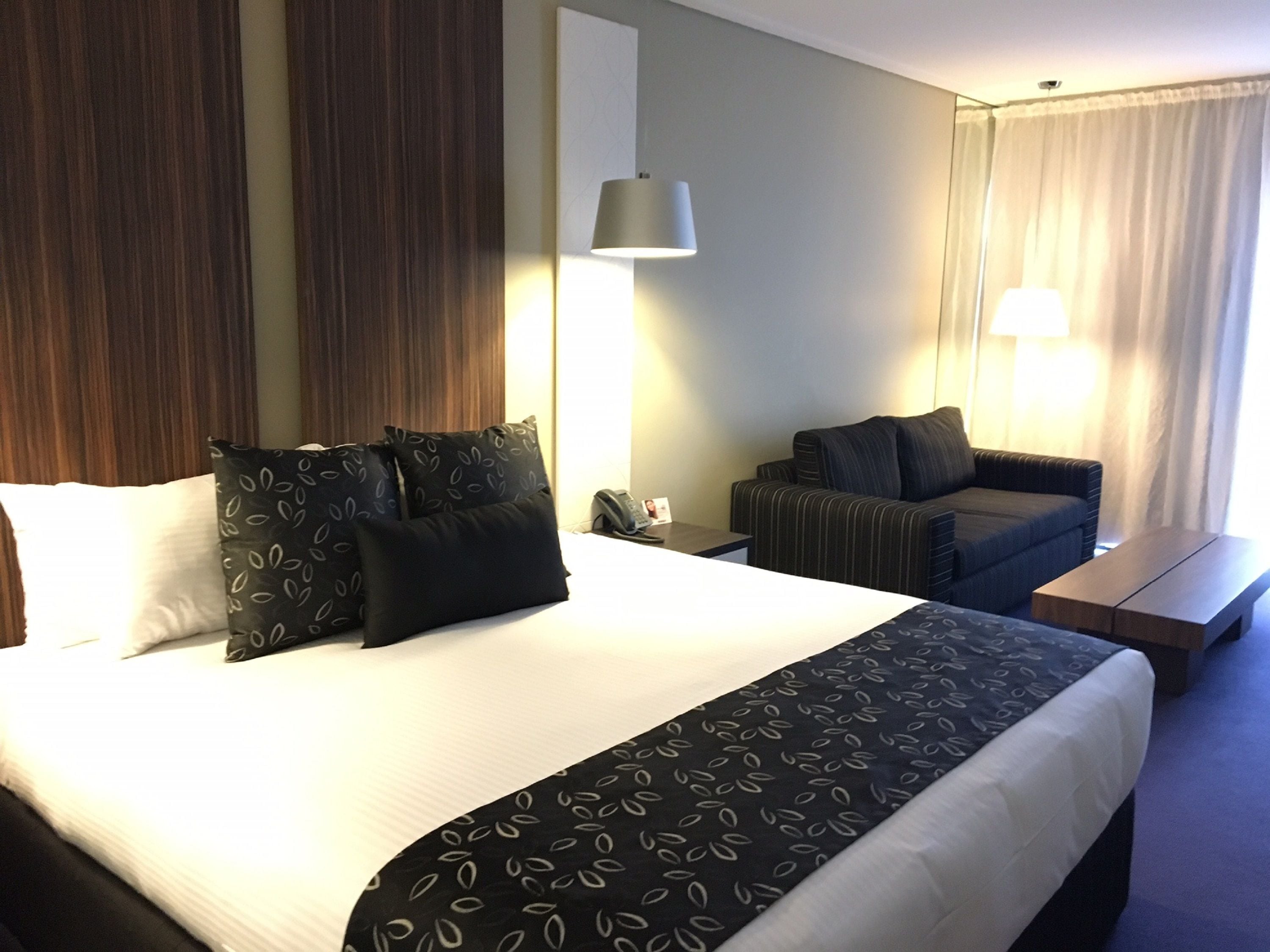 Una habitación de hotel con una cama grande, un sofá, un escritorio y una lámpara.