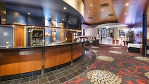 Un'accogliente hall d'albergo con una reception a forma di arco, una zona bar e un tappeto decorato.
