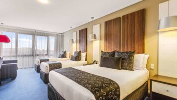 A hotel room with two beds, a sofa, and a desk.
