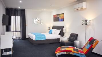 A modern hotel room with a bed, a desk, a chair, and a TV.