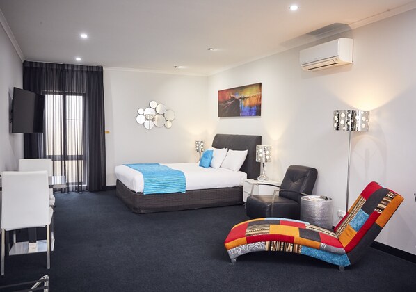 A modern hotel room with a bed, a desk, a chair, and a TV. - Junction Motel, Maryborough (Maryborough)