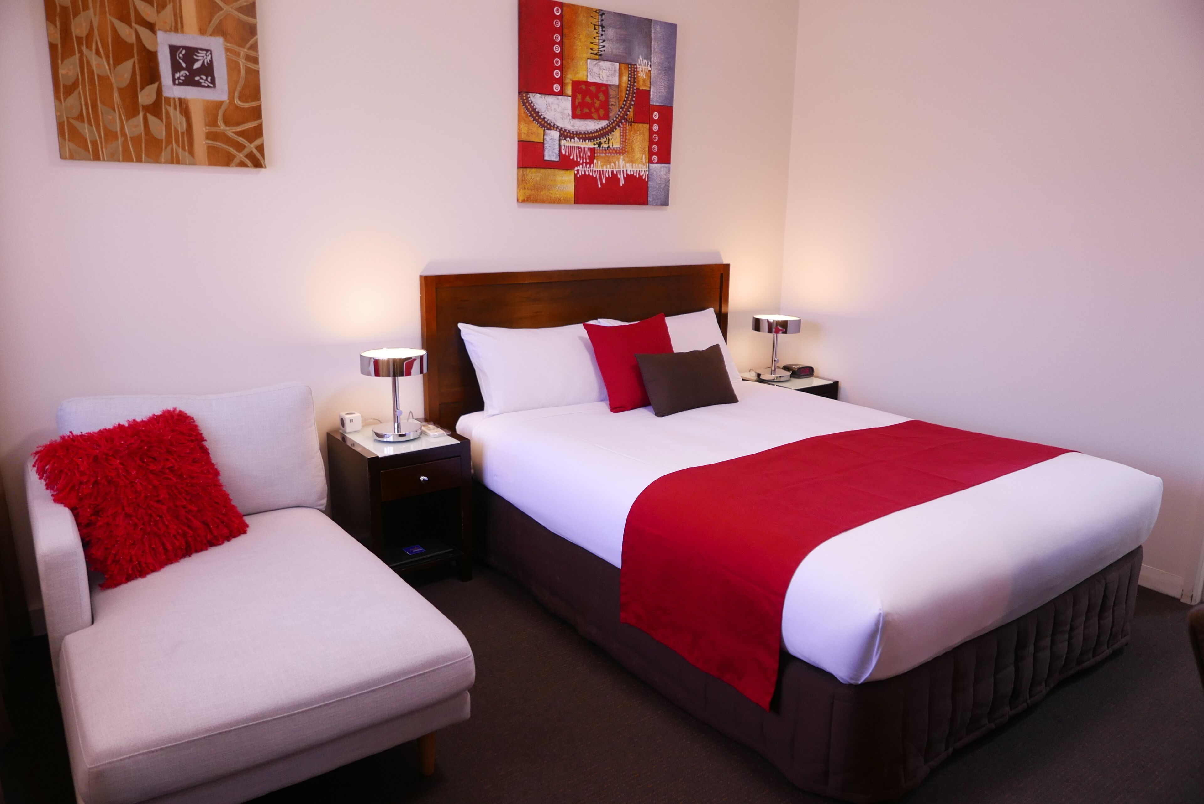 A hotel room with a bed, a chair, and two bedside tables.