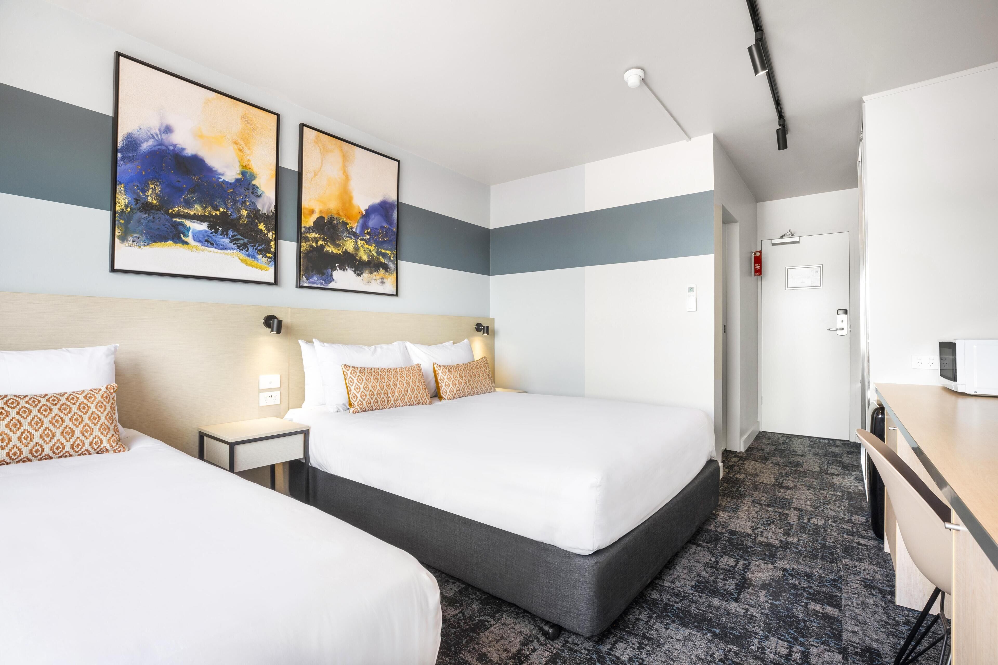 Habitación de hotel con una cama grande, un escritorio y dos cuadros en la pared.