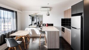 A modern kitchen with a central island, wooden chairs, and a dining table.