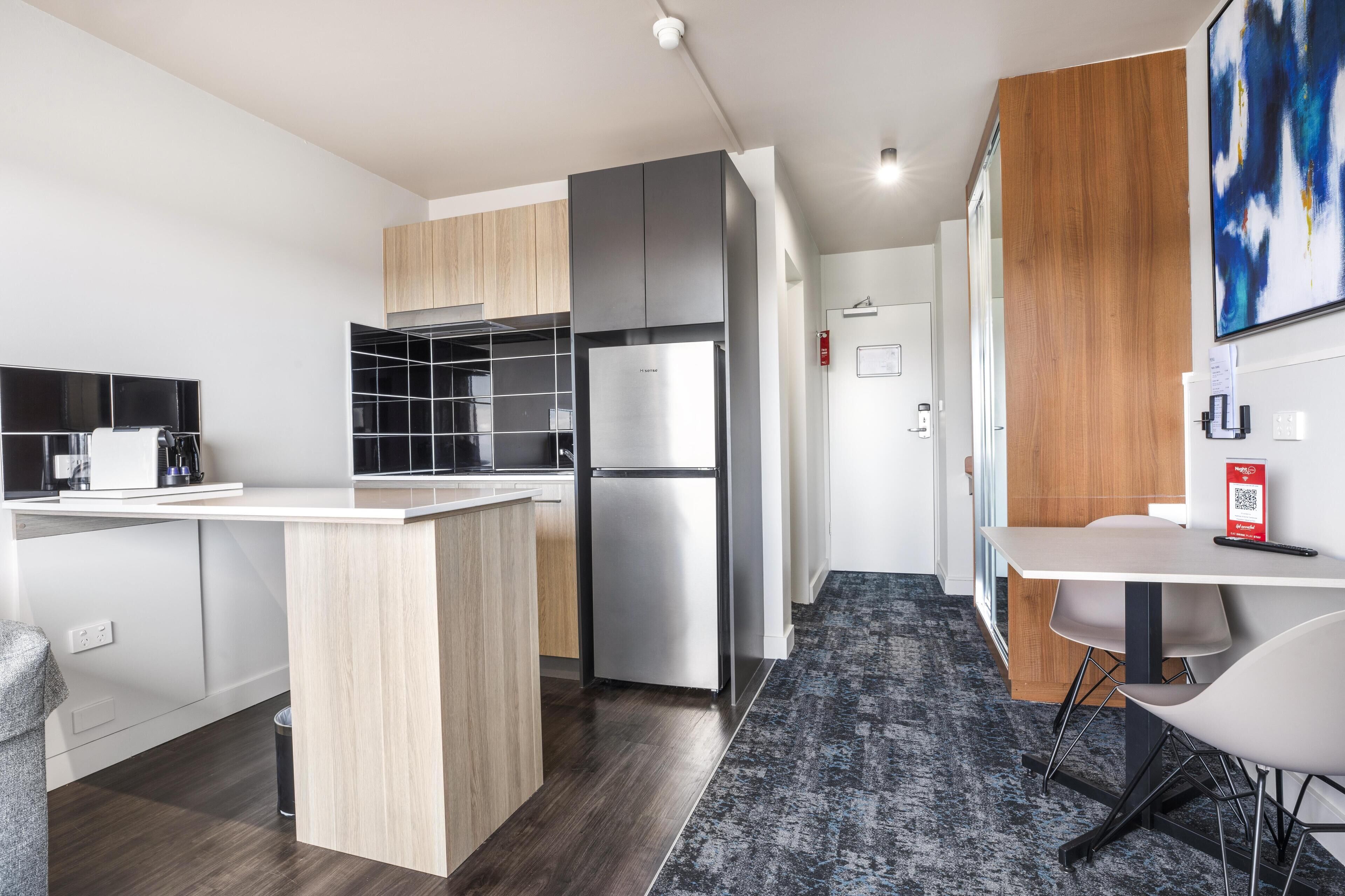A modern kitchen with a central island, built-in appliances, and a dining area with a table and chairs.