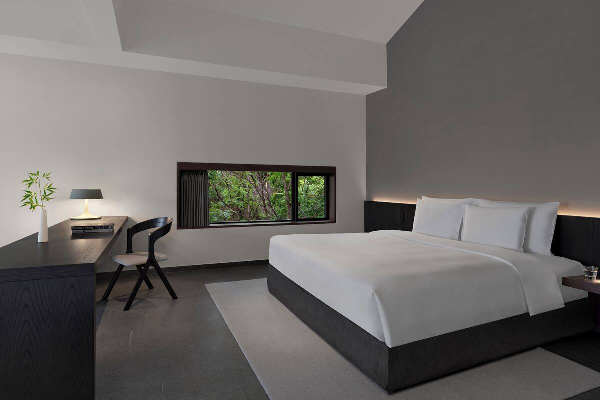 A modern bedroom with a large bed, a desk, and a chair.
