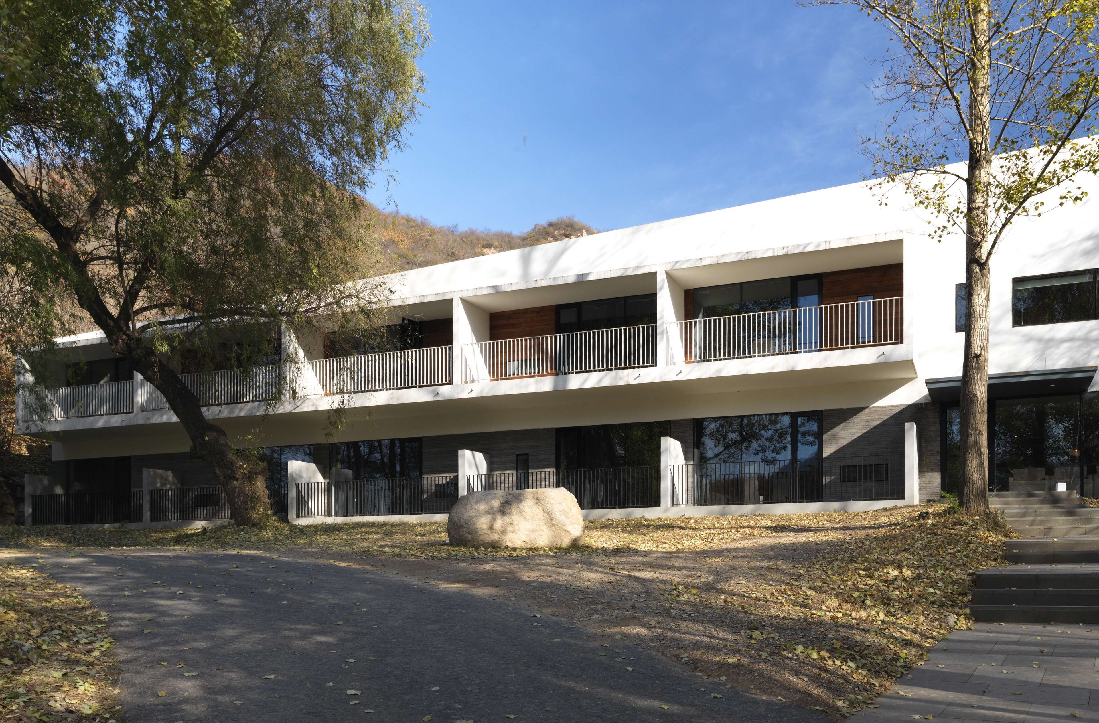Un bâtiment moderne doté d’un toit plat, de nombreux balcons et d’un chemin en pierre menant à l’entrée.