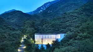 Une maison moderne entourée d  ’une forêt dense et de montagnes.