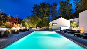 Une piscine avec des chaises longues et un bâtiment moderne en arrière-plan.