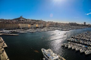Un puerto deportivo con barcos amarrados, un paisaje urbano al fondo y un cielo despejado.