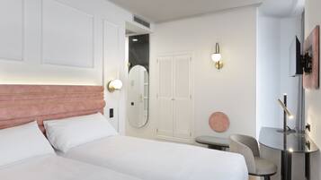 Una habitación de hotel con cama, mesita de noche, silla y espejo.