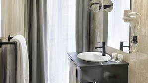 A modern bathroom with a large mirror, a sink, and a hairdryer mounted on the wall. - Hotel Inca (Zaragoza)