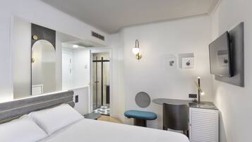 Una habitación de hotel moderna con una cama grande, un escritorio, una silla, una mesita y un espejo.