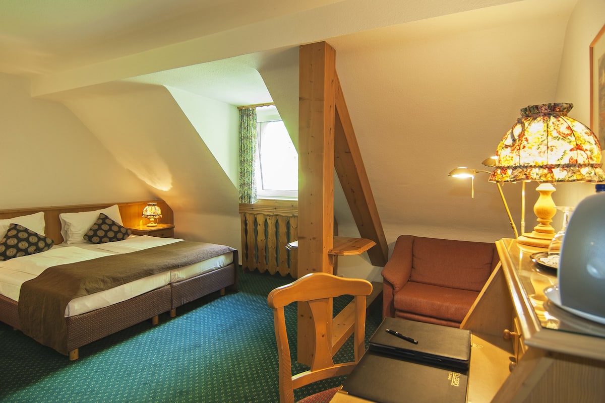 Une chambre à coucher avec un lit, une chaise, un bureau et une lampe.