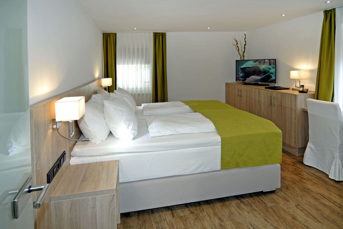 Une chambre d’hôtel équipée d’un lit, d’un bureau, d’une chaise, d’une télévision et d’une lampe.