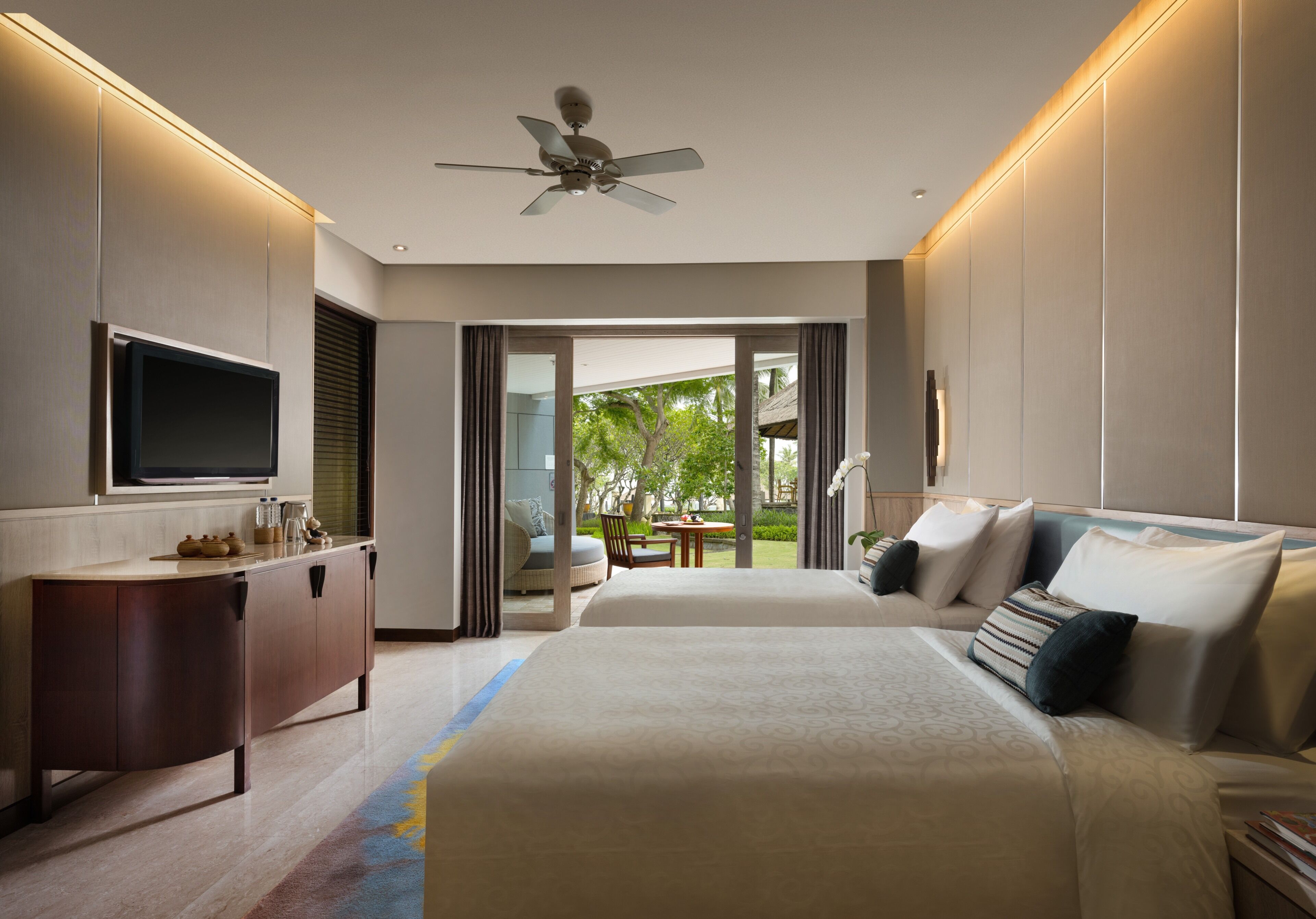 A hotel room with a bed, a TV, a desk, and a view of the outdoors.