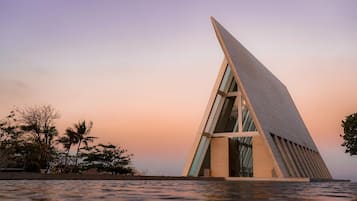 A modern building with a unique triangular design, large windows, and a waterfront view.