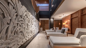 Experience the unique, intricately carved wall featuring naturalistic designs, alongside a stylish seating area with leather armchairs.