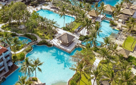 Un resort con varias piscinas, palmeras y edificios del complejo.