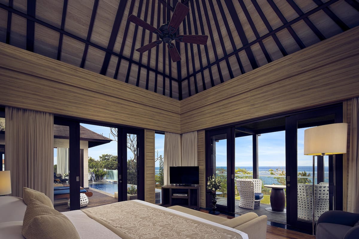 Un dormitorio amplio con una cama grande, ventilador de techo, televisión y vistas al océano.