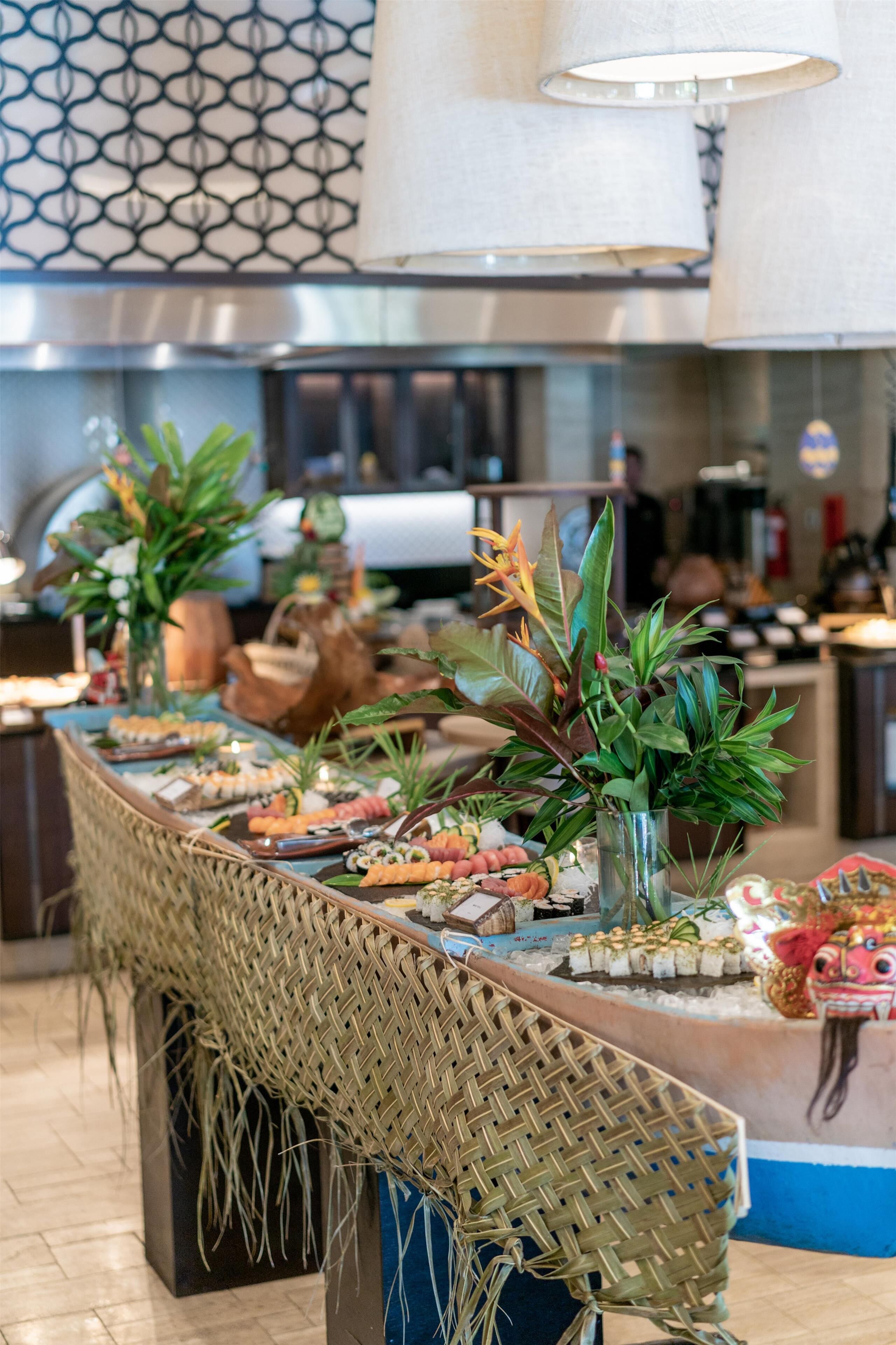 Una mesa de buffet con diversos alimentos y plantas decorativas.