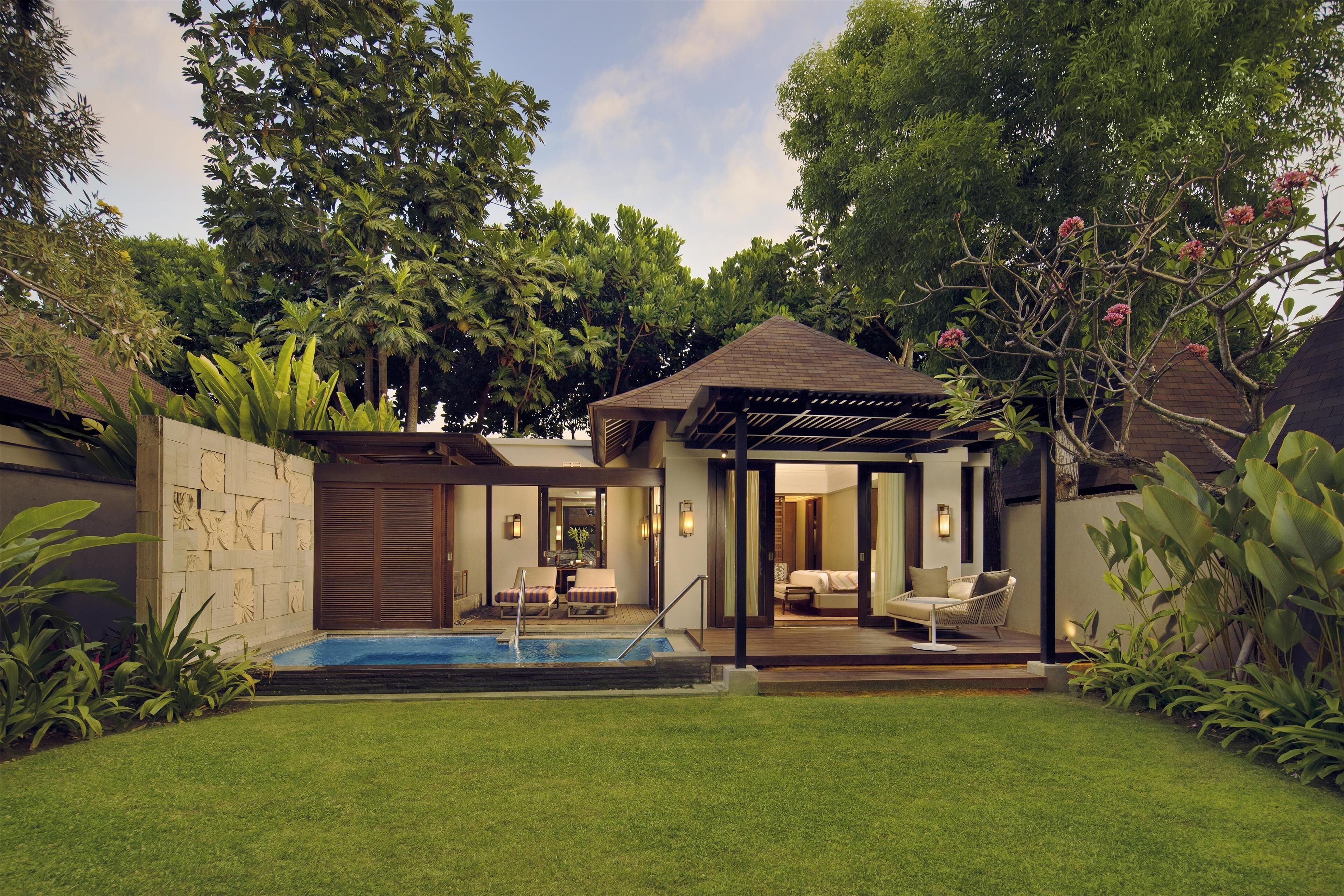 A modern house with a swimming pool, outdoor seating, and lush greenery.