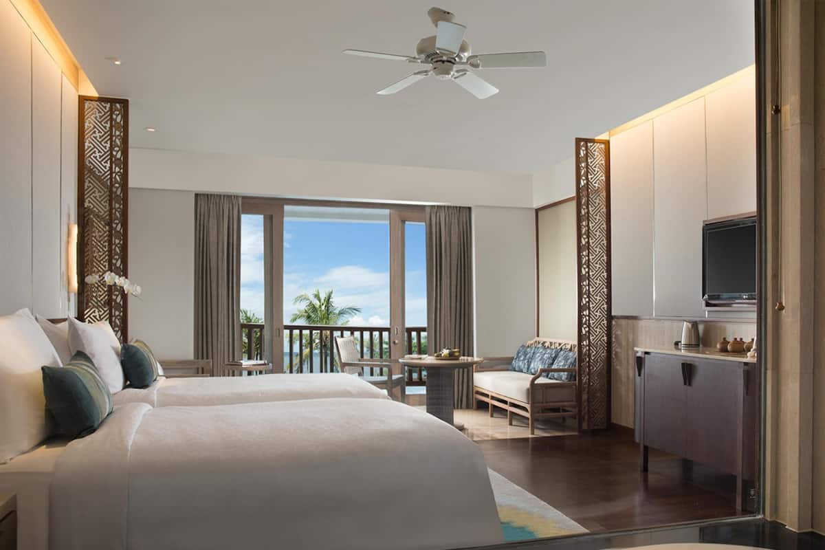 Una habitación de hotel con cama, balcón, escritorio y televisor.