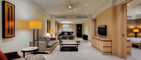 A hotel room with a living area, a kitchen, a TV, and a bed.