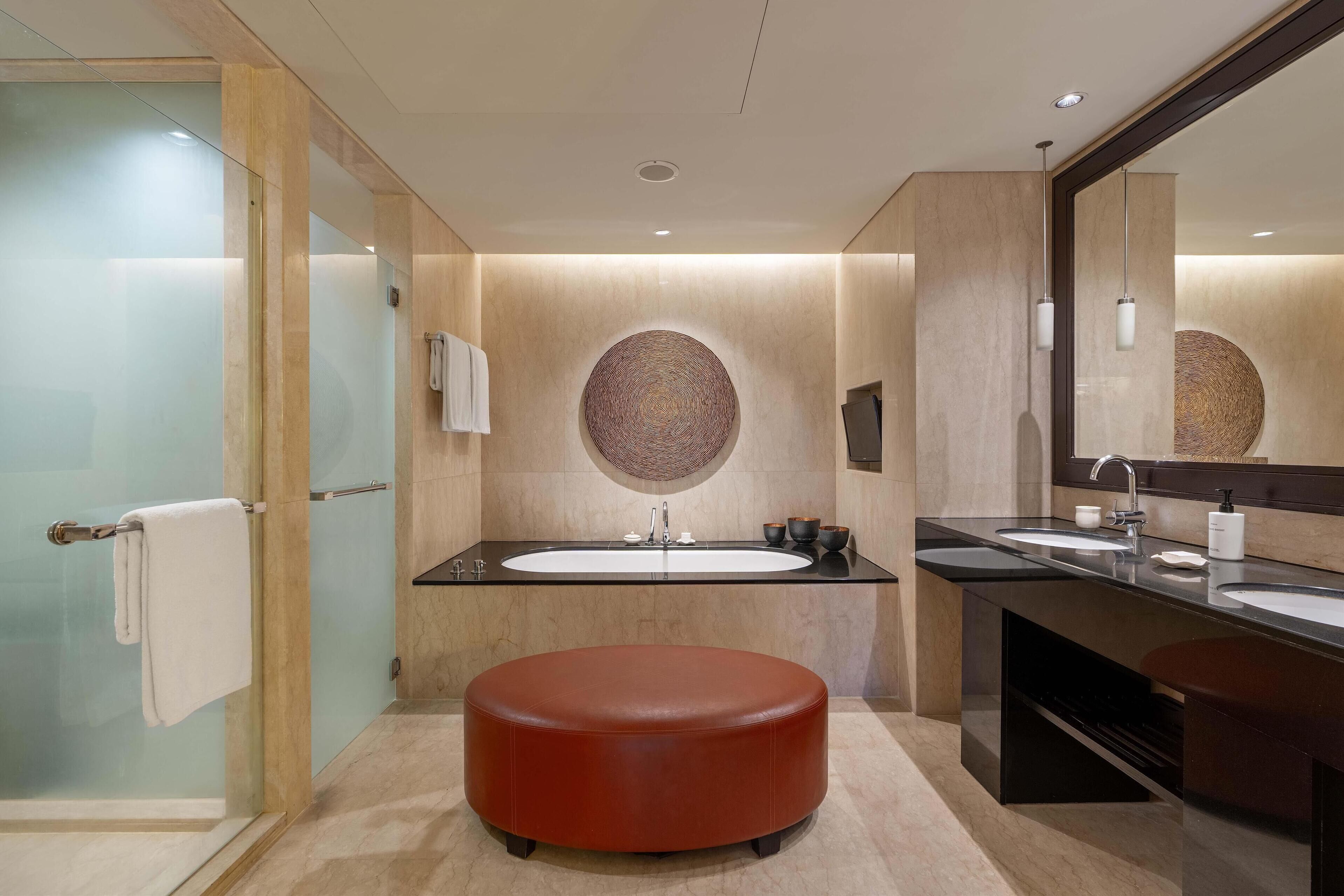 A modern bathroom with a glass shower enclosure, a round mirror, and a large oval sink.
