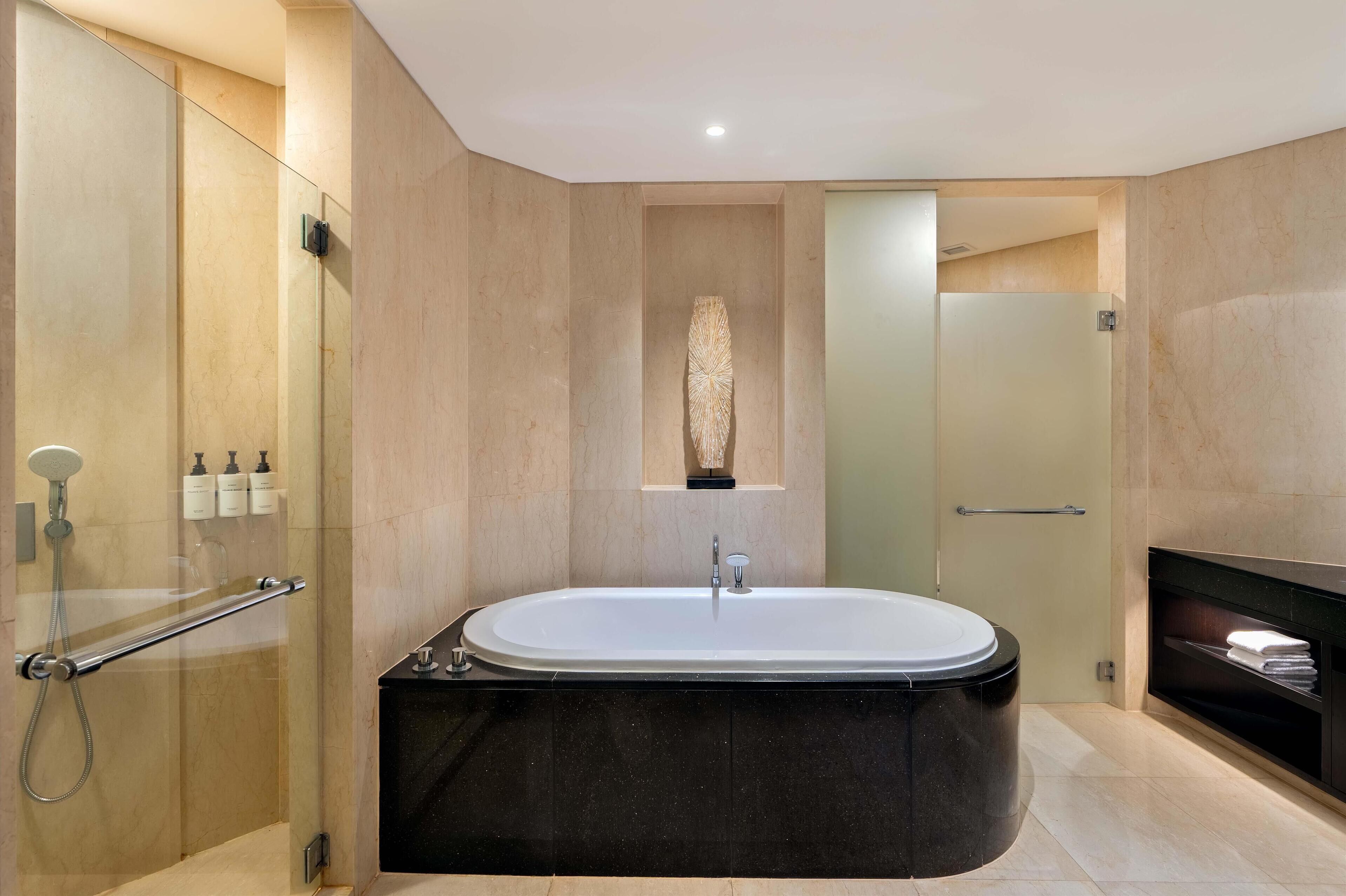 A modern bathroom with a freestanding bathtub, a glass-enclosed shower, and a built-in fireplace.