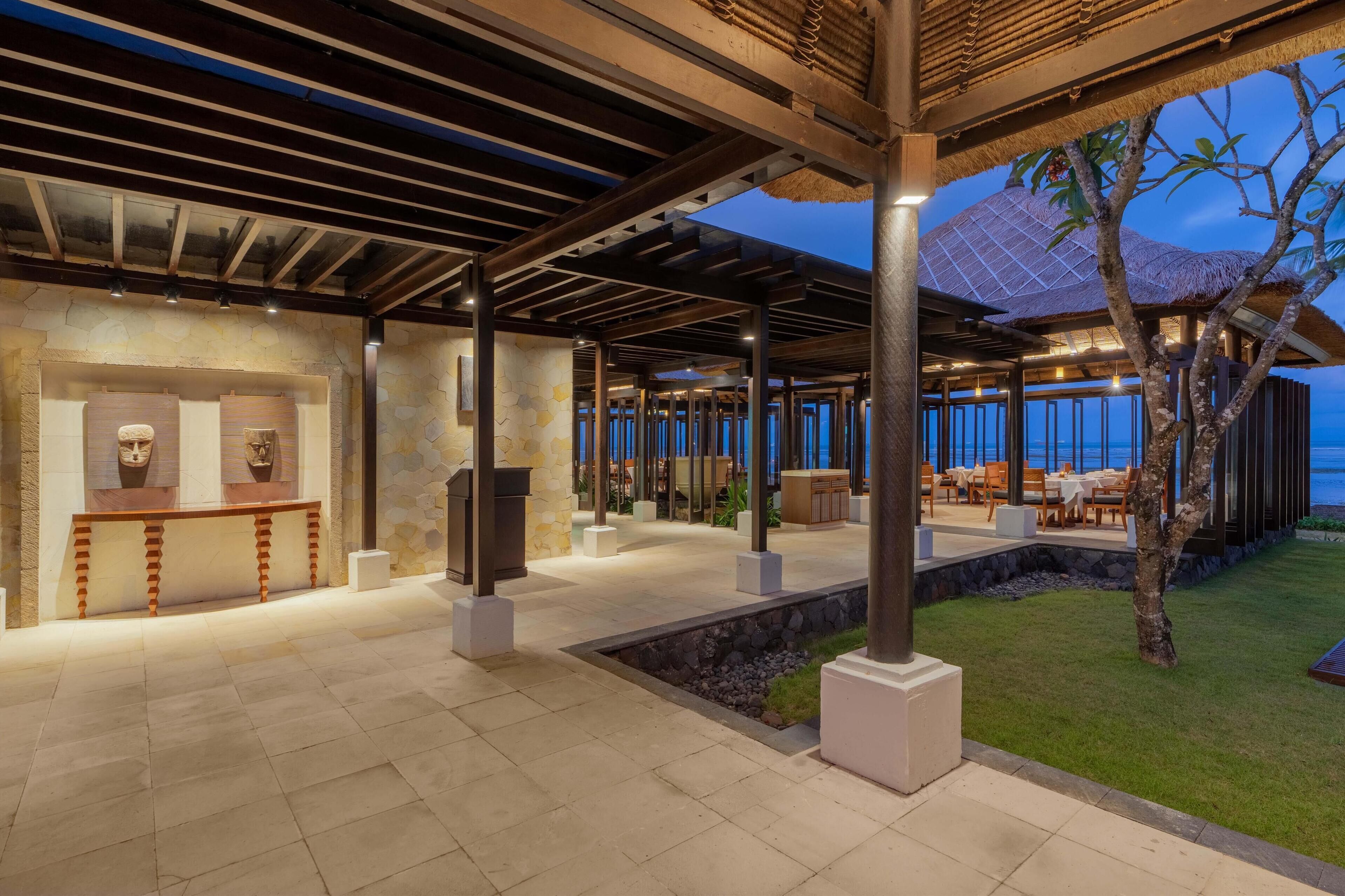 A covered outdoor area with stone walls, a bench, and a dining area with tables and chairs.