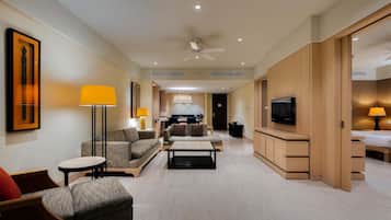 A spacious hotel room with a living area, a dining area, and a bedroom.