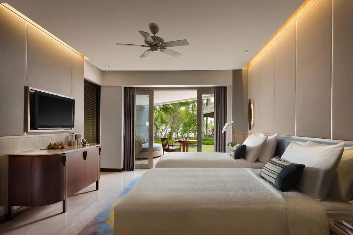 Habitación de hotel con una cama grande, televisión, escritorio y vistas al exterior.