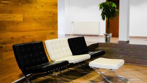 Un espace d’attente avec un mur en bois, une plante en pot et un coin salon comprenant un banc et une petite table.