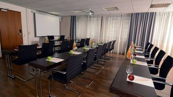 A conference room with a long table, chairs, a projector screen, and a whiteboard.