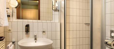 A bathroom with a sink, mirror, and glass-enclosed shower.