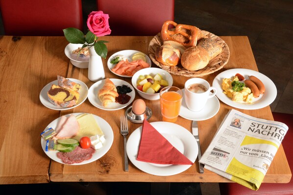 Une table de petit-déjeuner avec divers aliments, un journal et une rose.