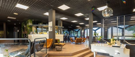 A modern interior with a reception desk, seating area, and a piano.