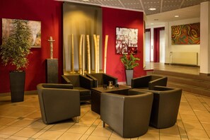 Un vestíbulo con muebles modernos, una planta grande y arte abstracto en las paredes.