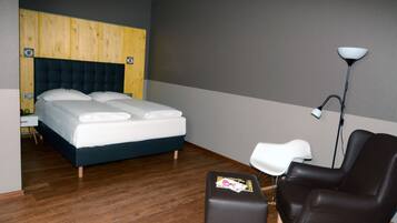 A hotel room with a bed, a desk, a chair, and a floor lamp.