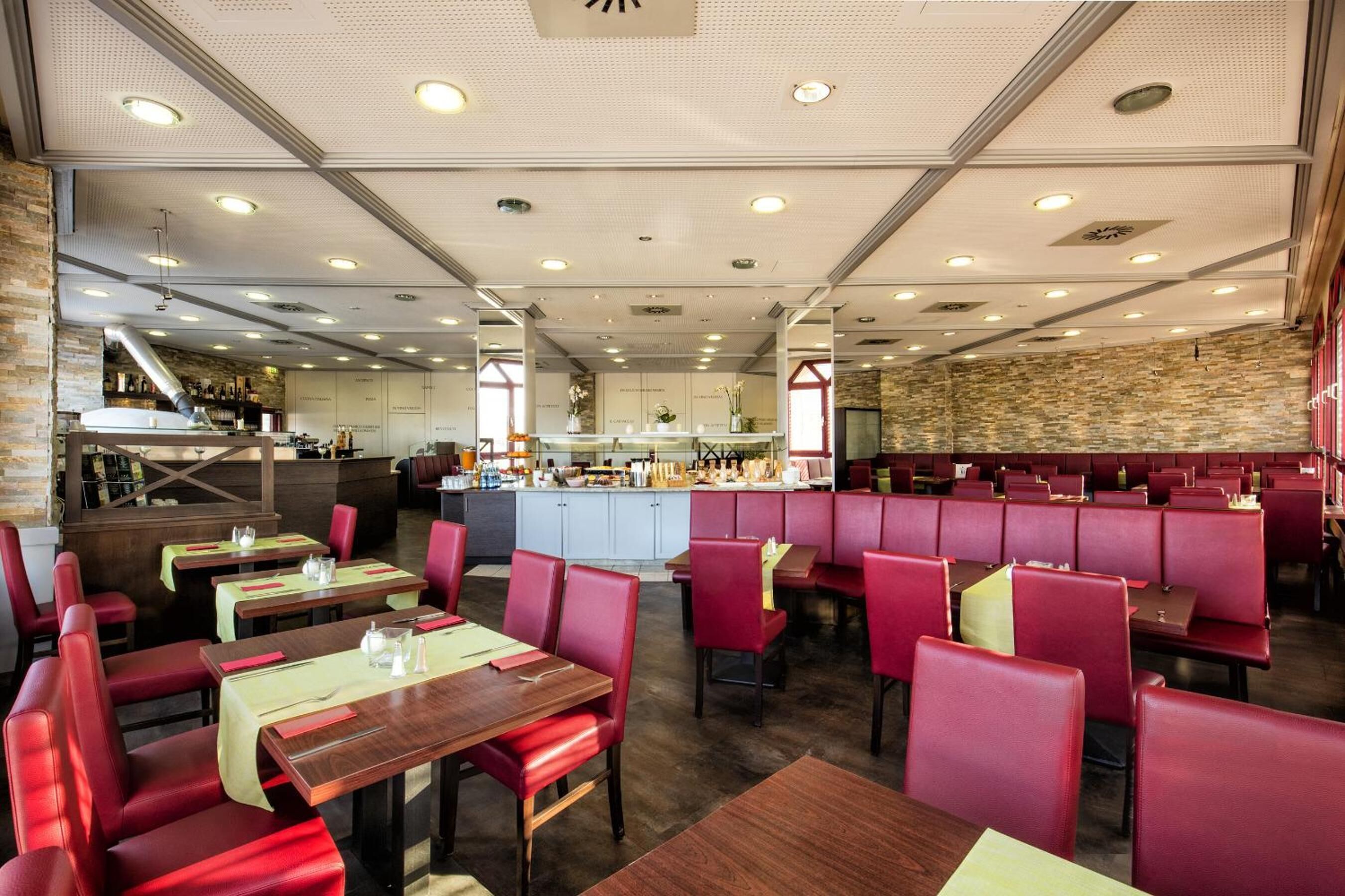 A restaurant with red booths and tables, a kitchen area, and a bar.
