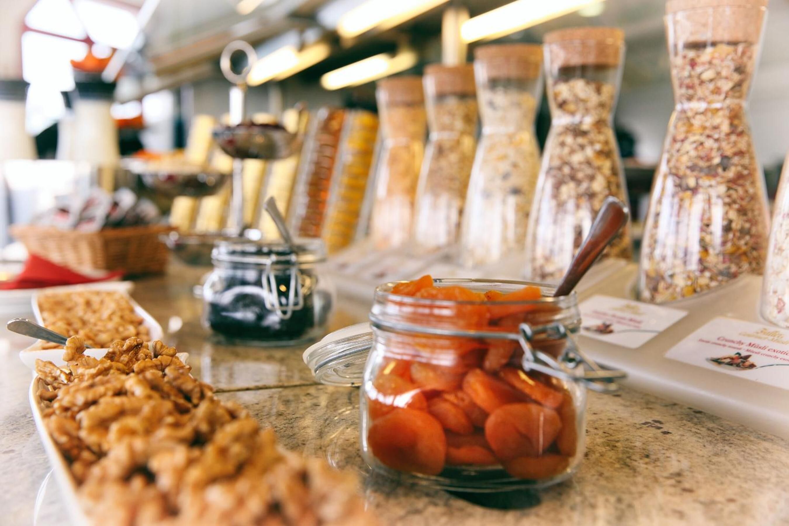 Ein reichhaltiges Buffet mit verschiedenen Speisen, darunter Granola, Trockenfrüchte und Nüsse.