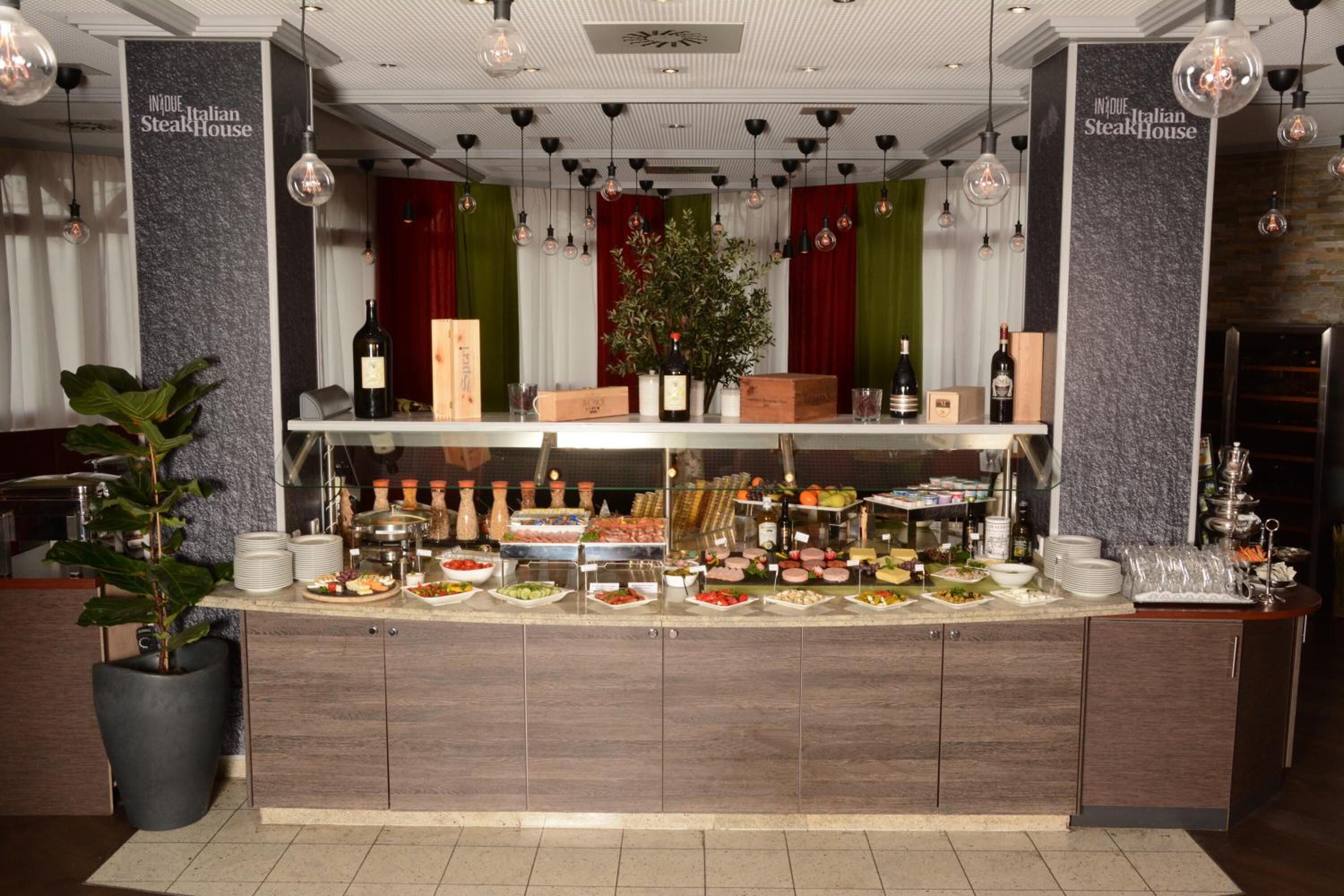 A buffet setup with various food items and condiments, a potted plant, and a sign reading "INNOUE Italian Steak House".