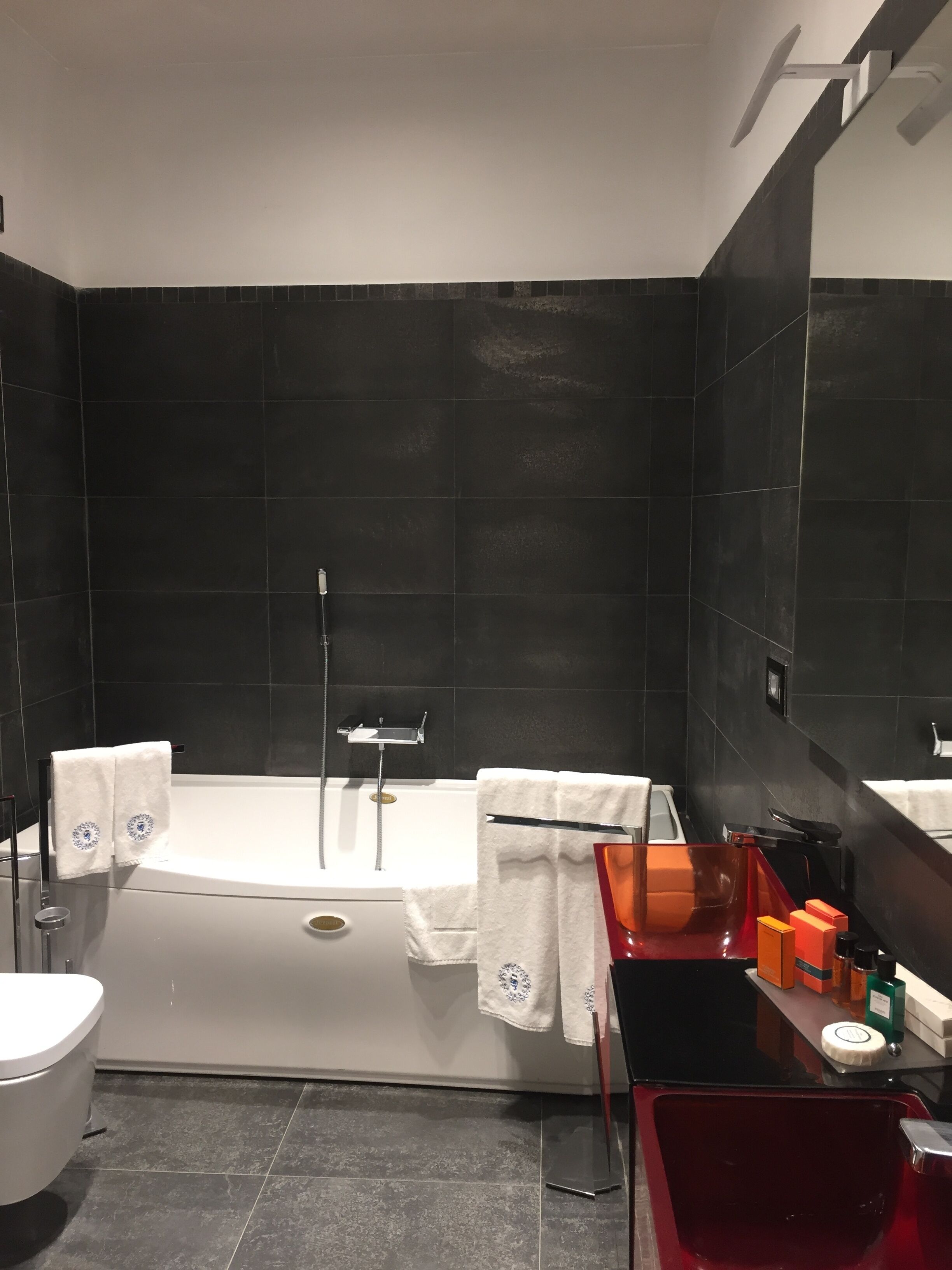 Ett modernt badrum med badkar, toalett och ett handfat med tillhörande hygienartiklar.