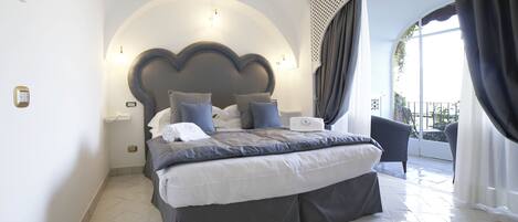 Une chambre moderne avec un grand lit, une tête de lit intégrée et un balcon agrémenté de rideaux.