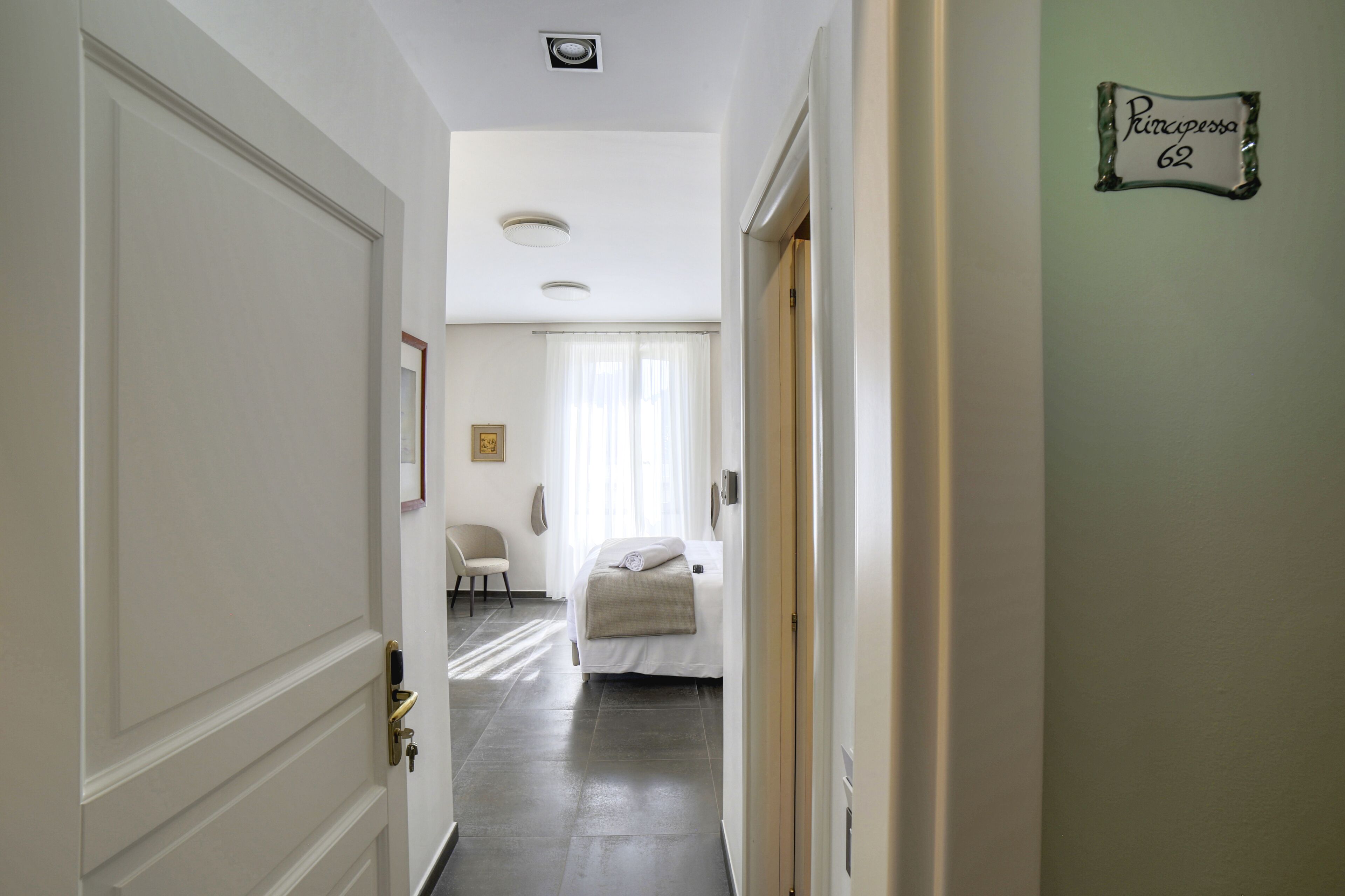 A hotel hallway with a bed, a chair, and a sign on the wall.