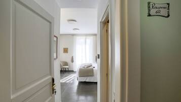 A hotel hallway with a bed, a chair, and a sign on the wall.