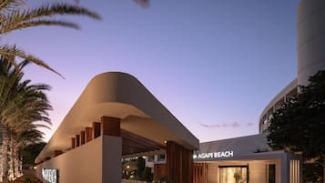 Un bâtiment moderne à la façade incurvée, sur lequel on peut lire l’inscription « AGAPI BEACH ».